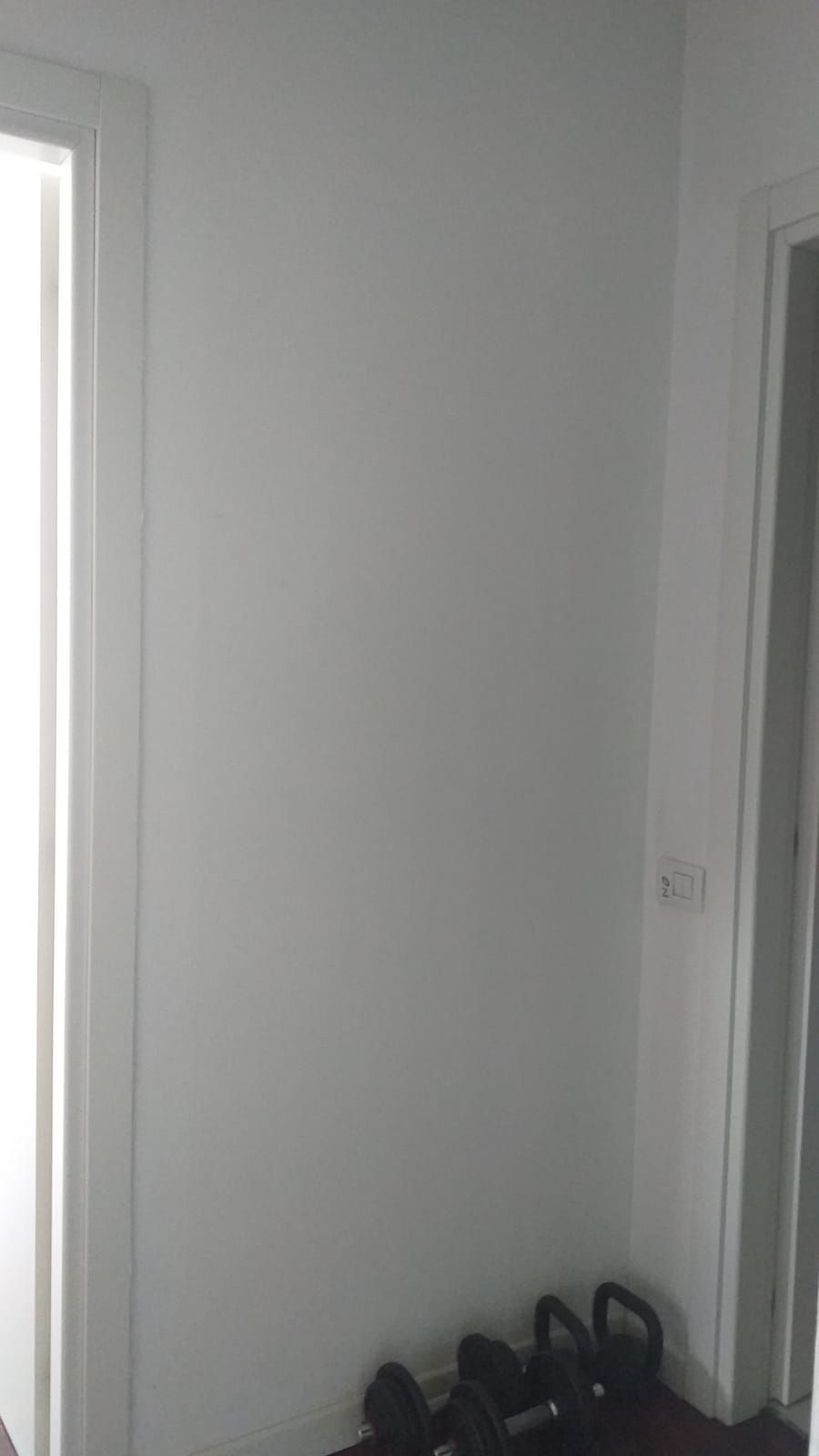 Parete bianca con kettlebell sul pavimento vicino a una porta e una finestra.