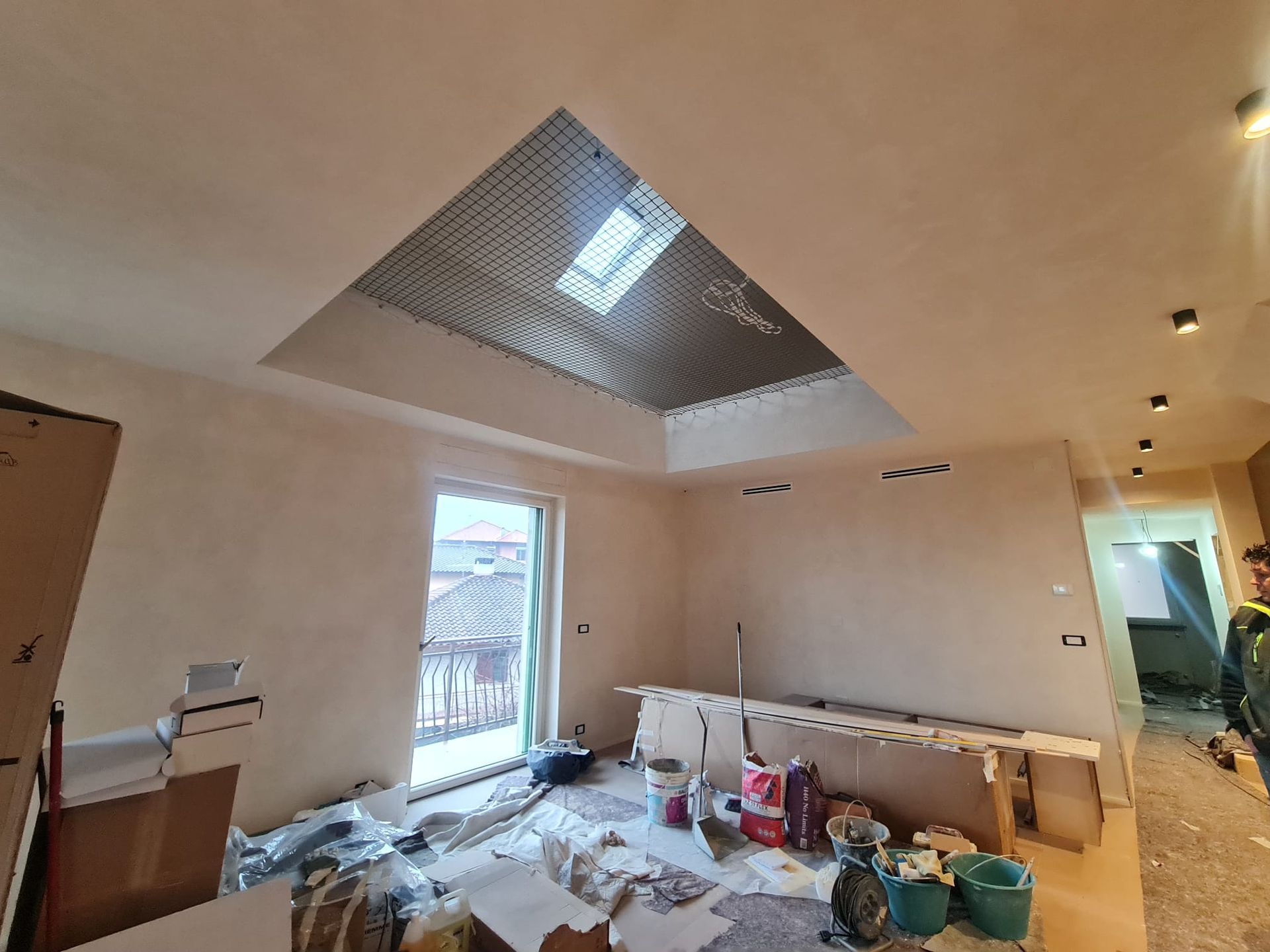 Stanza in fase di ristrutturazione con lucernario, finestra e materiali da costruzione.