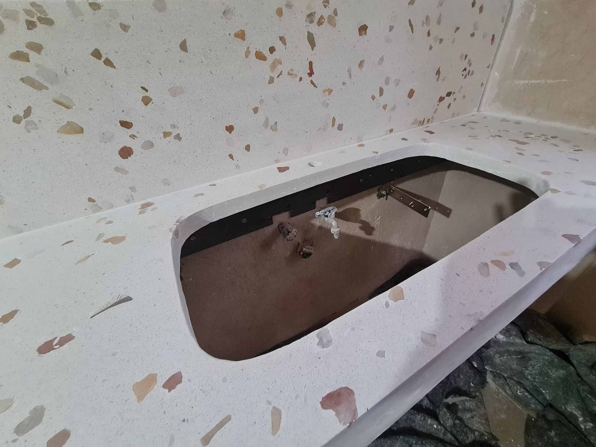 Piano di lavoro bianco con dettagli screziati e un lavello rettangolare.