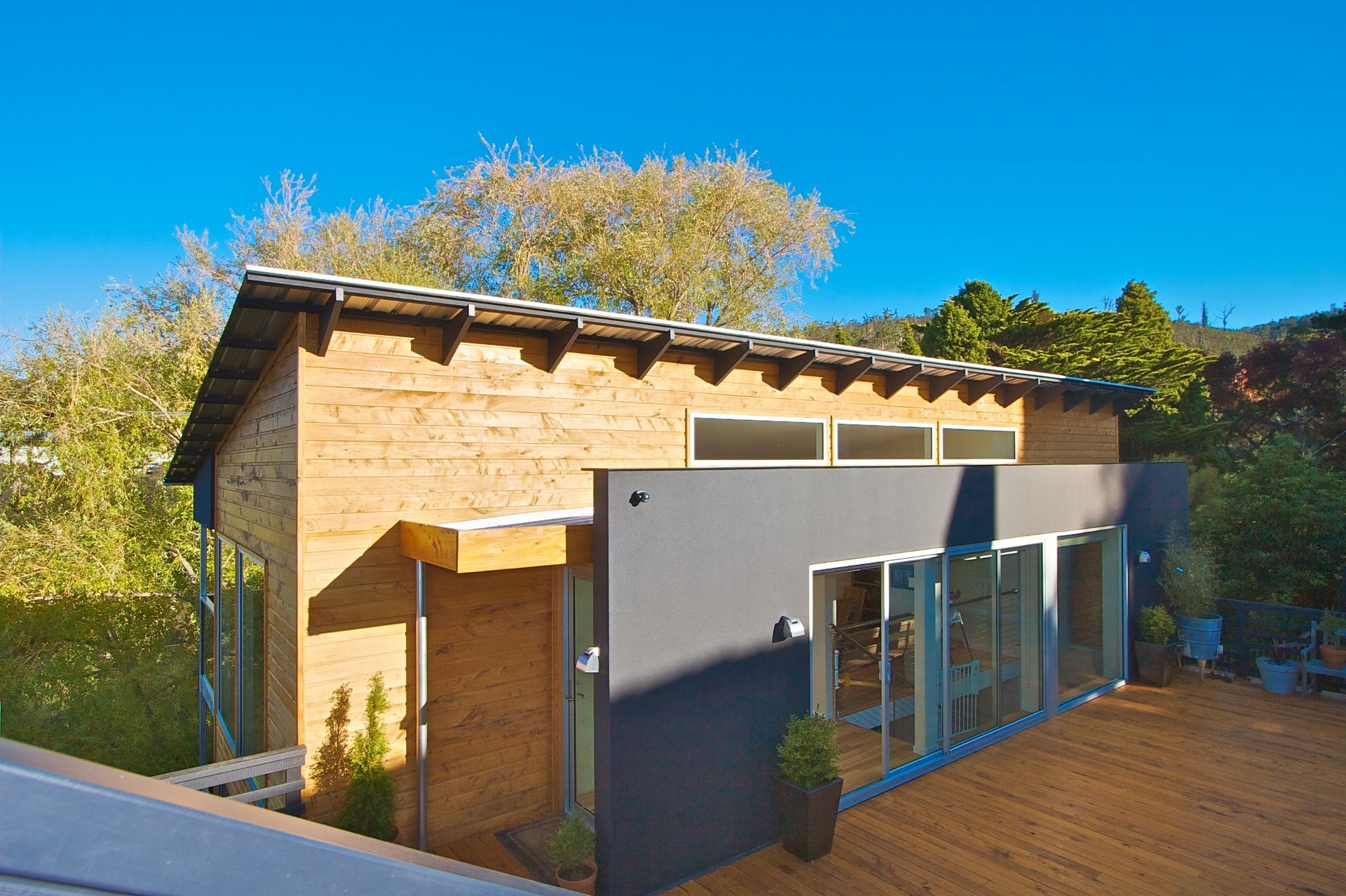 A small house with a lot of windows and a wooden deck