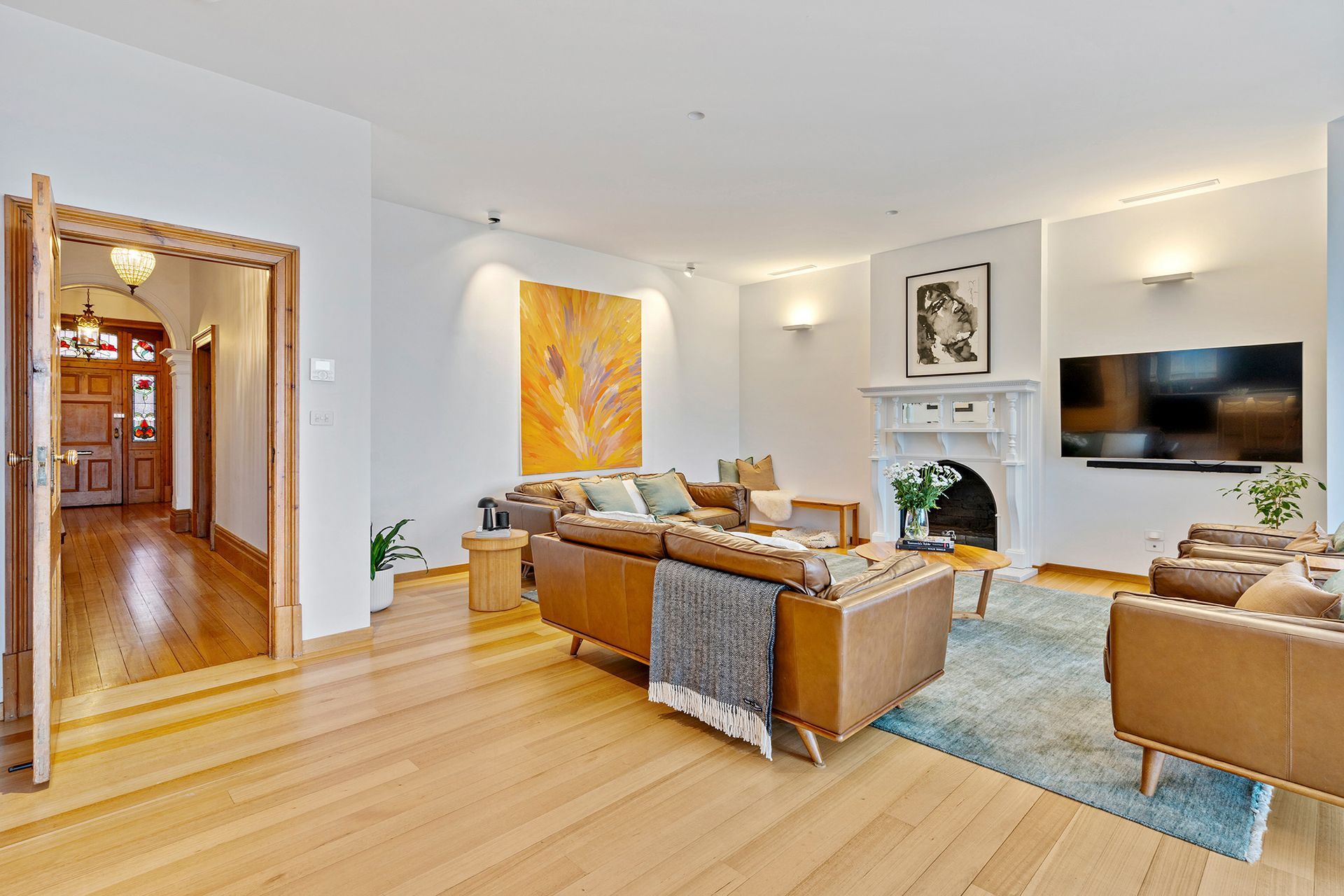A living room with a couch , chairs , television and fireplace.