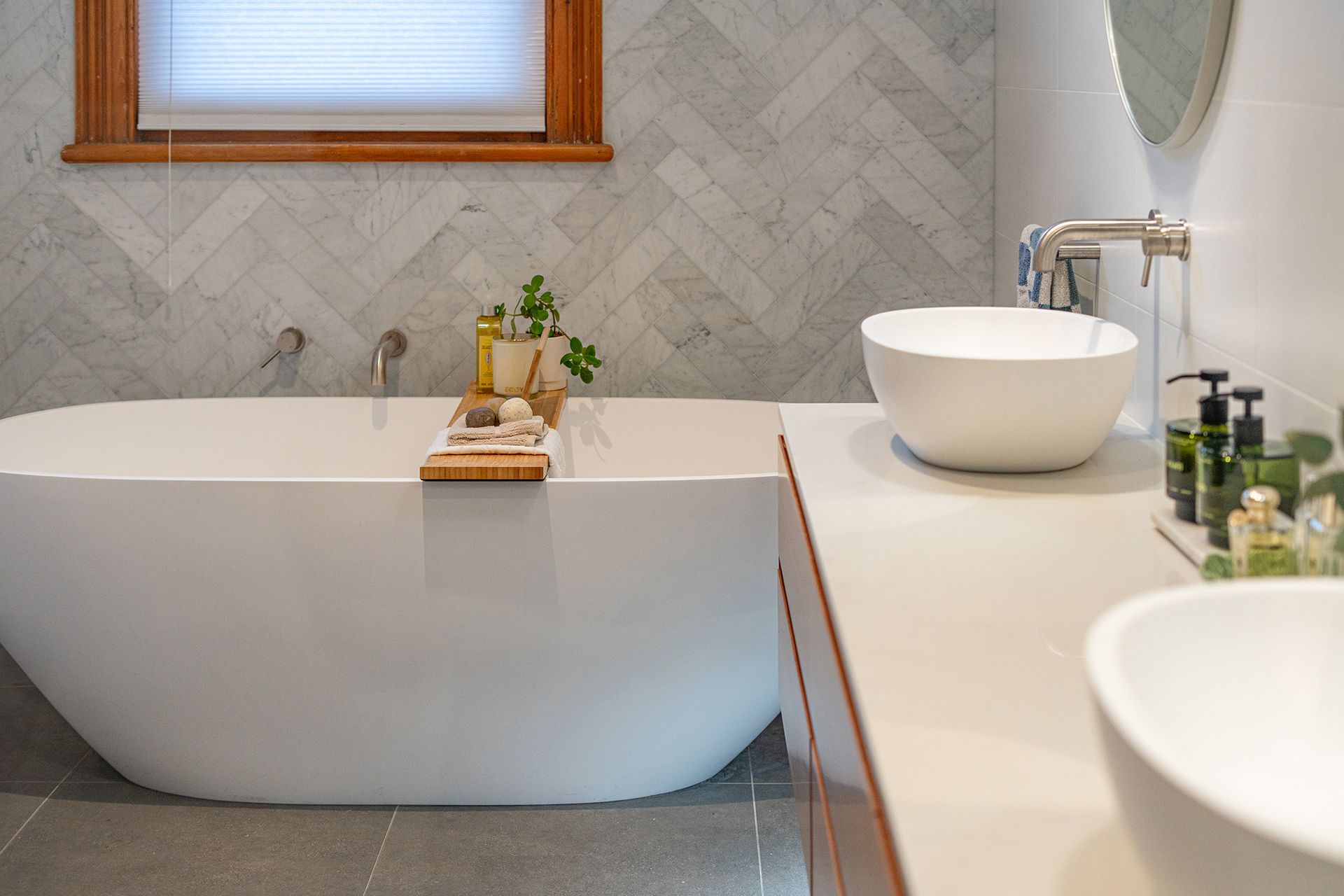 A bathroom with a bathtub , sink , mirror and window.