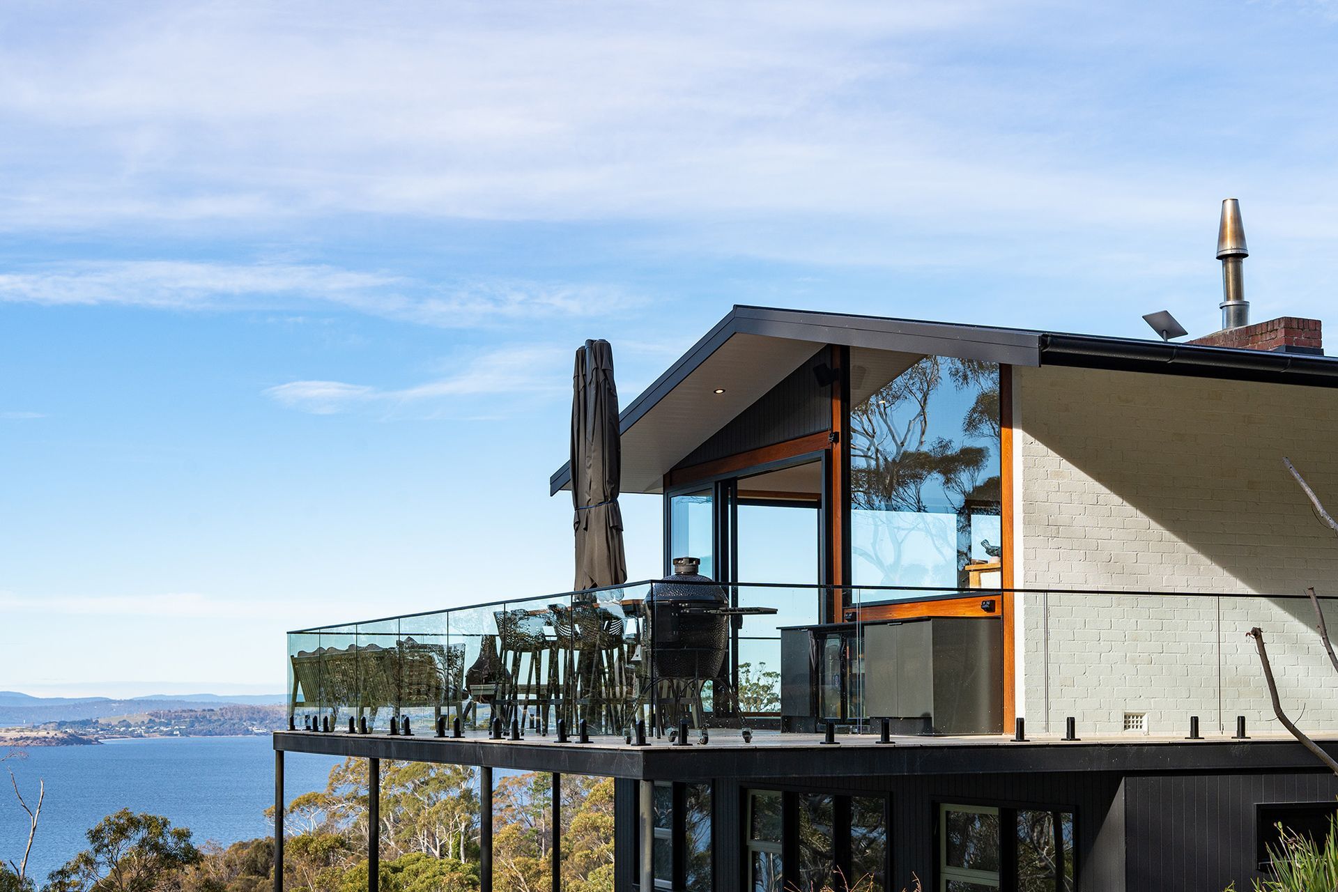 A modern house with a large balcony overlooking the ocean.