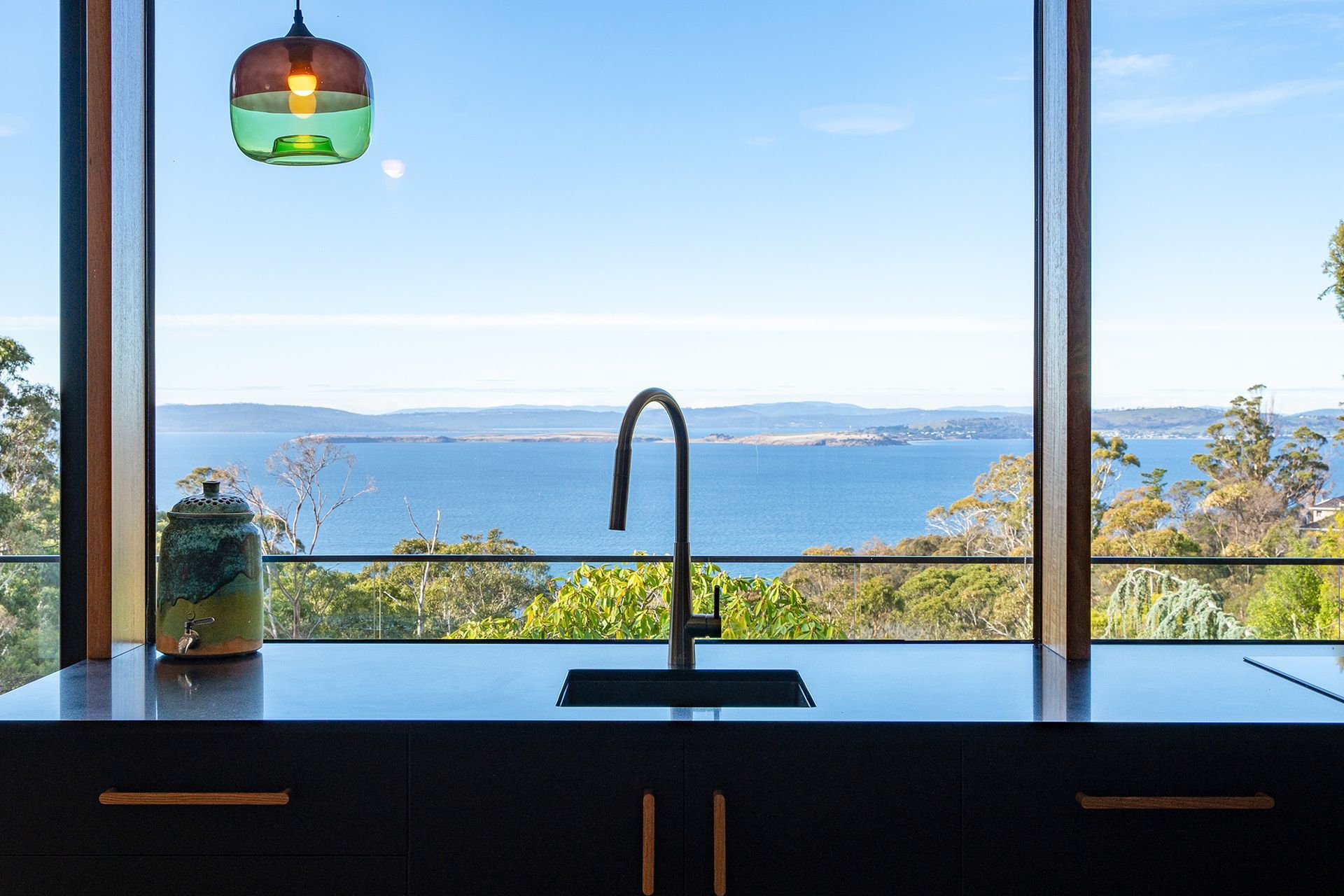 A kitchen with a sink and a view of the ocean.
