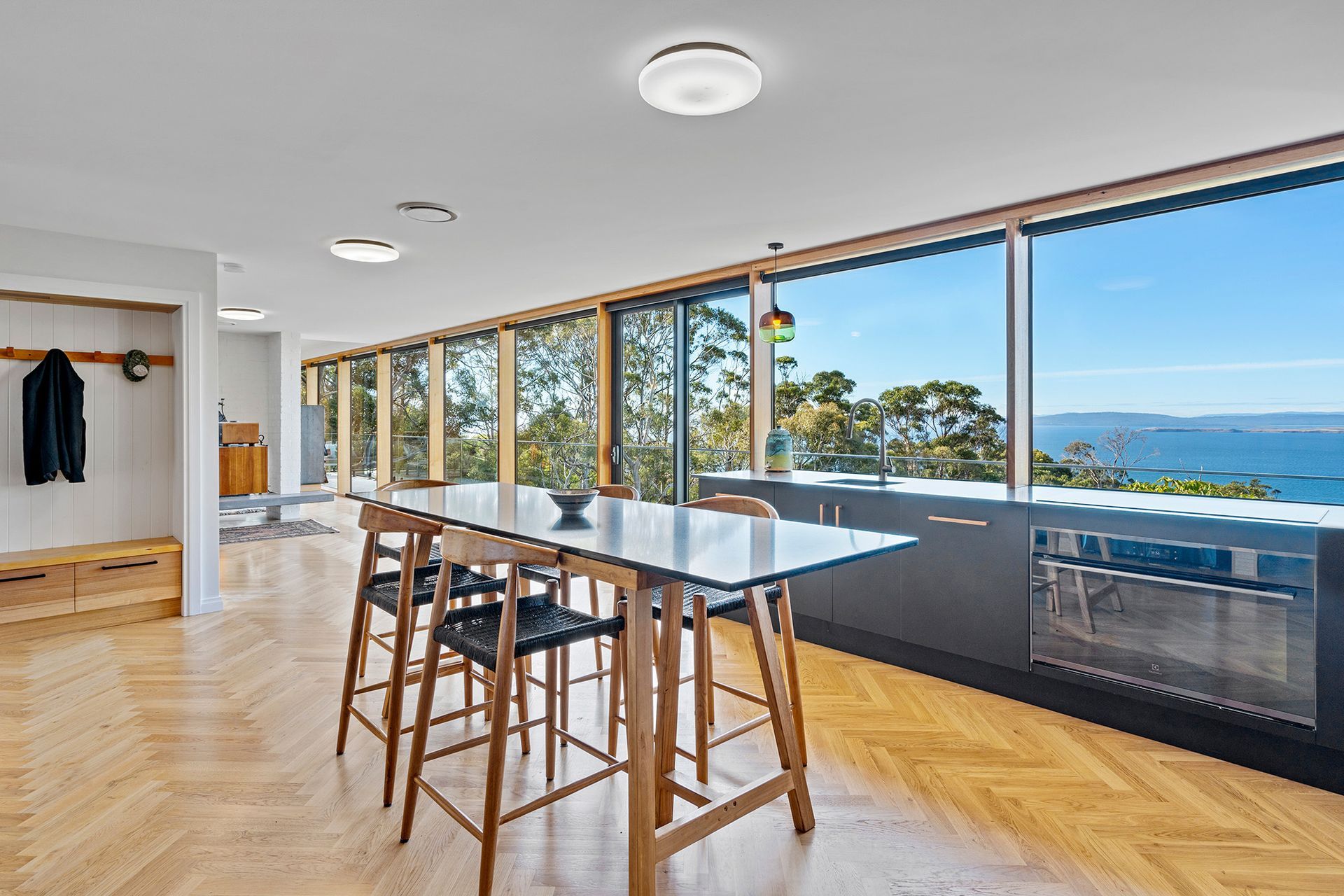 A dining room with a table and chairs and a view of the ocean.