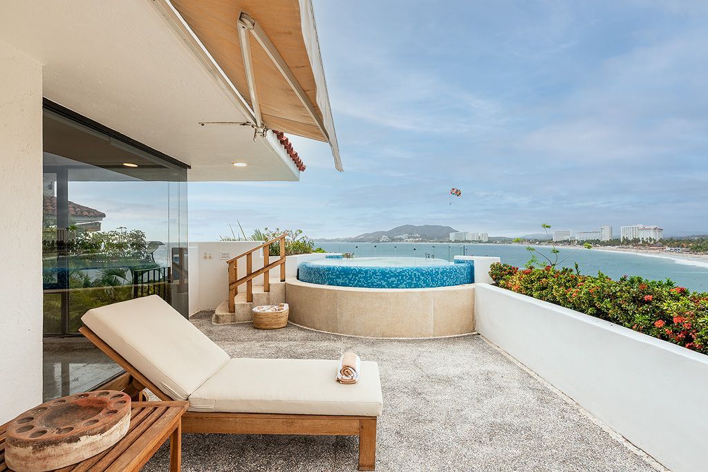 Lujosa terraza frente al mar con tumbona, jacuzzi y vistas al mar.
