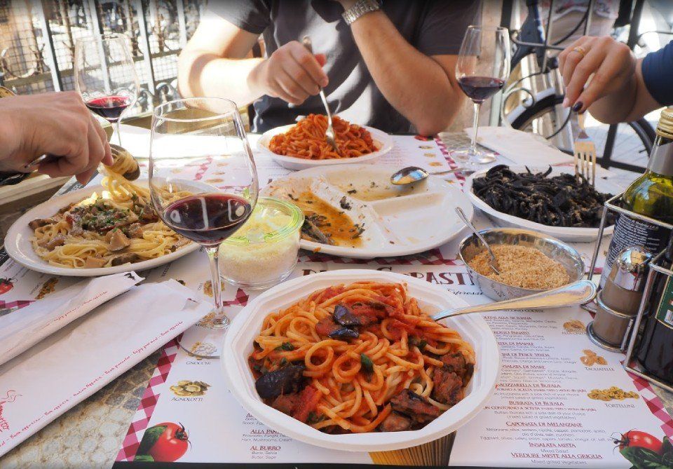 Ospiti al tavolo con primi piatti di pasta fresca