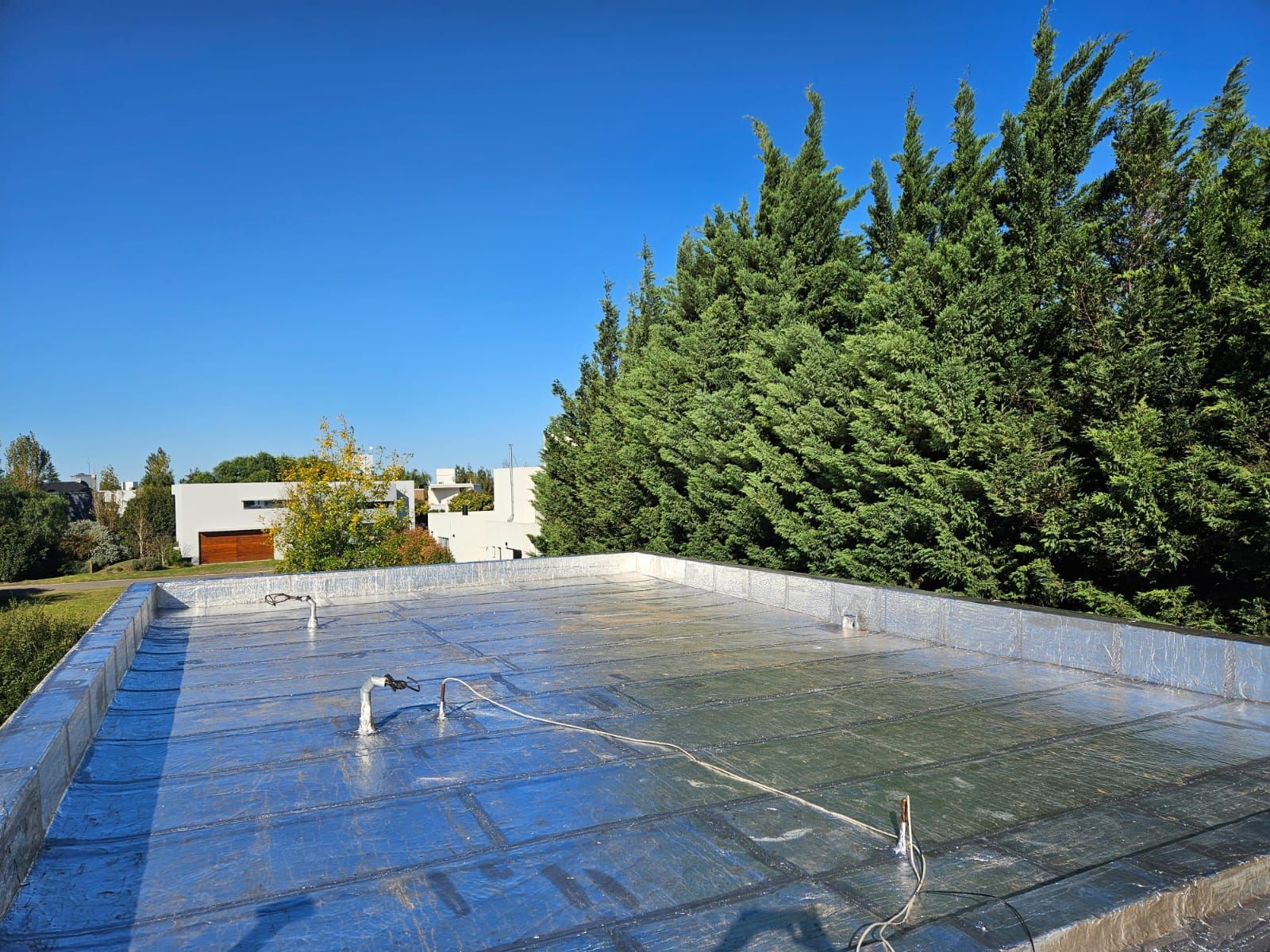 Un tejado con árboles al fondo y una casa al fondo.