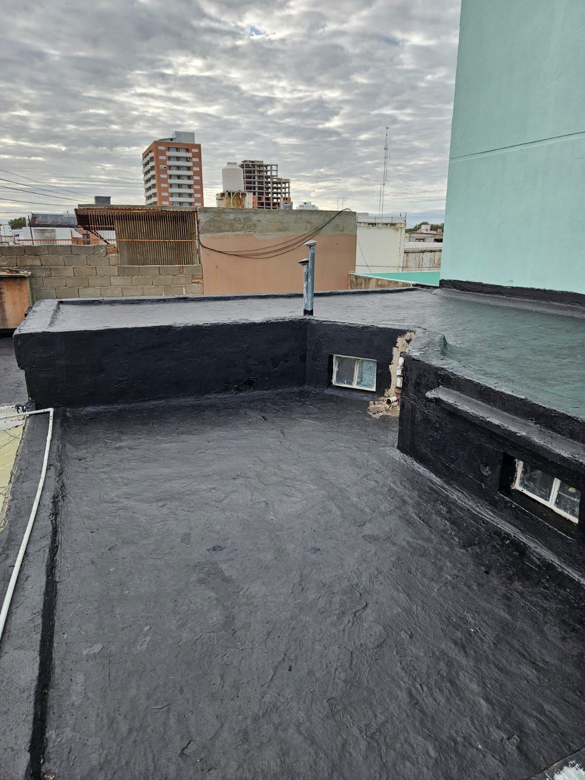 Una azotea con un techo negro y una ciudad al fondo.