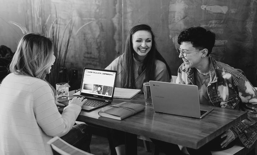 A group of people are sitting at a table with laptops.