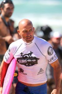 A man in a surf shirt is holding a pink surfboard
