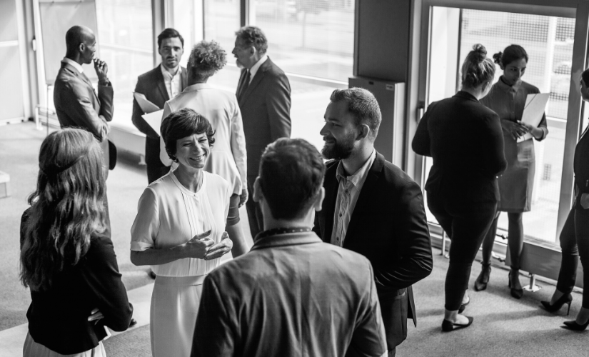 A group of people are standing in a room talking to each other.