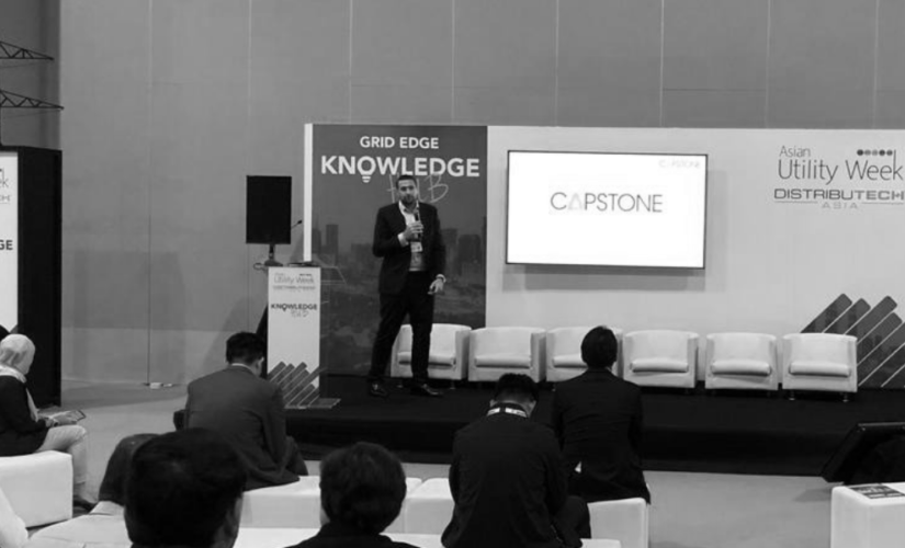 A man is standing on a stage giving a presentation to a group of people.