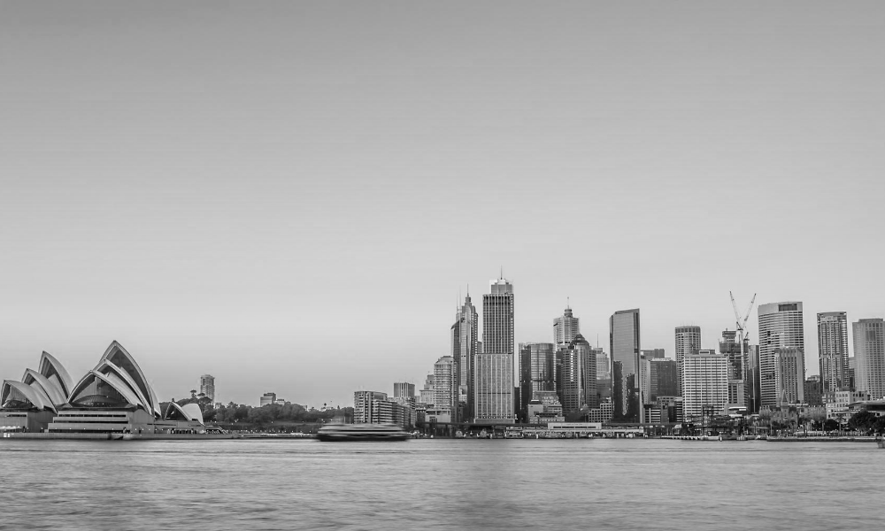 A black and white photo of a city skyline with the opera house in the foreground.