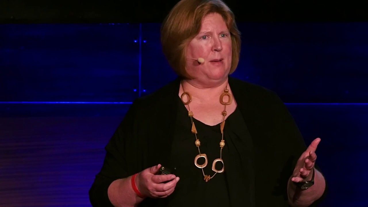 A woman is giving a speech on a stage in front of a microphone.