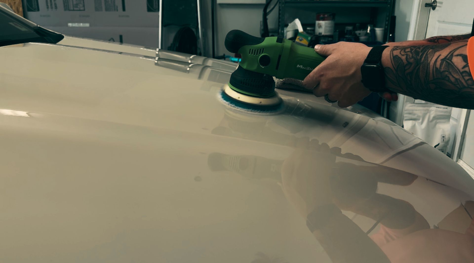 A man is polishing a white car with a machine.