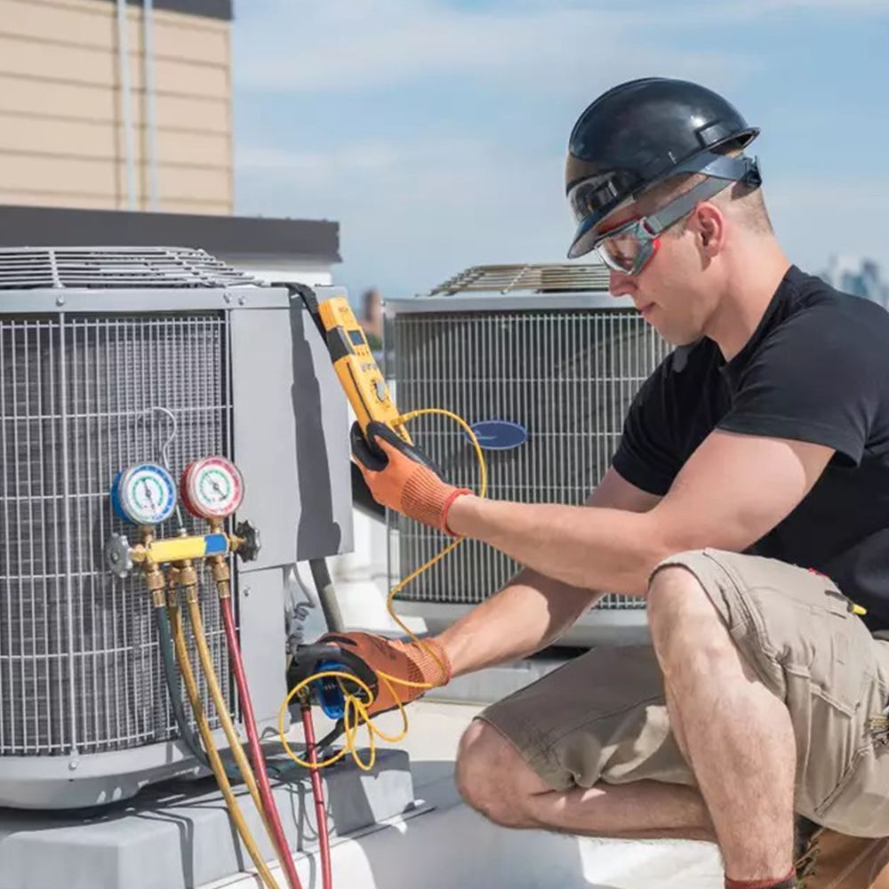 A man is working on an air conditioner on a rooftop.