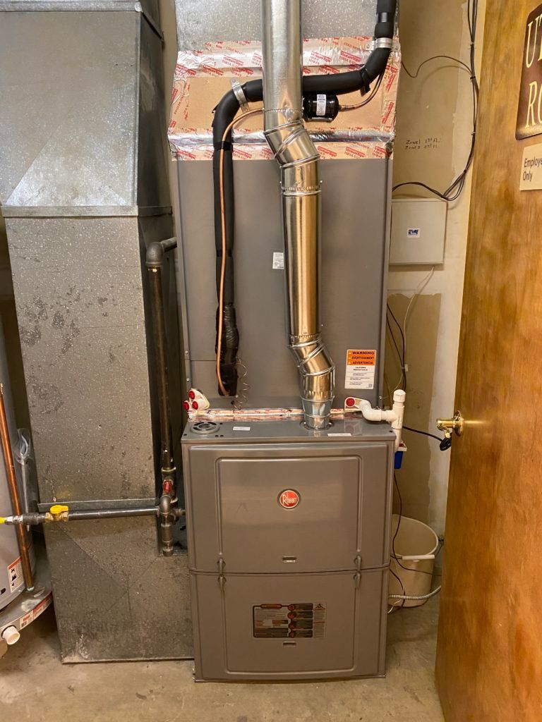 A furnace is sitting in a basement next to a door.