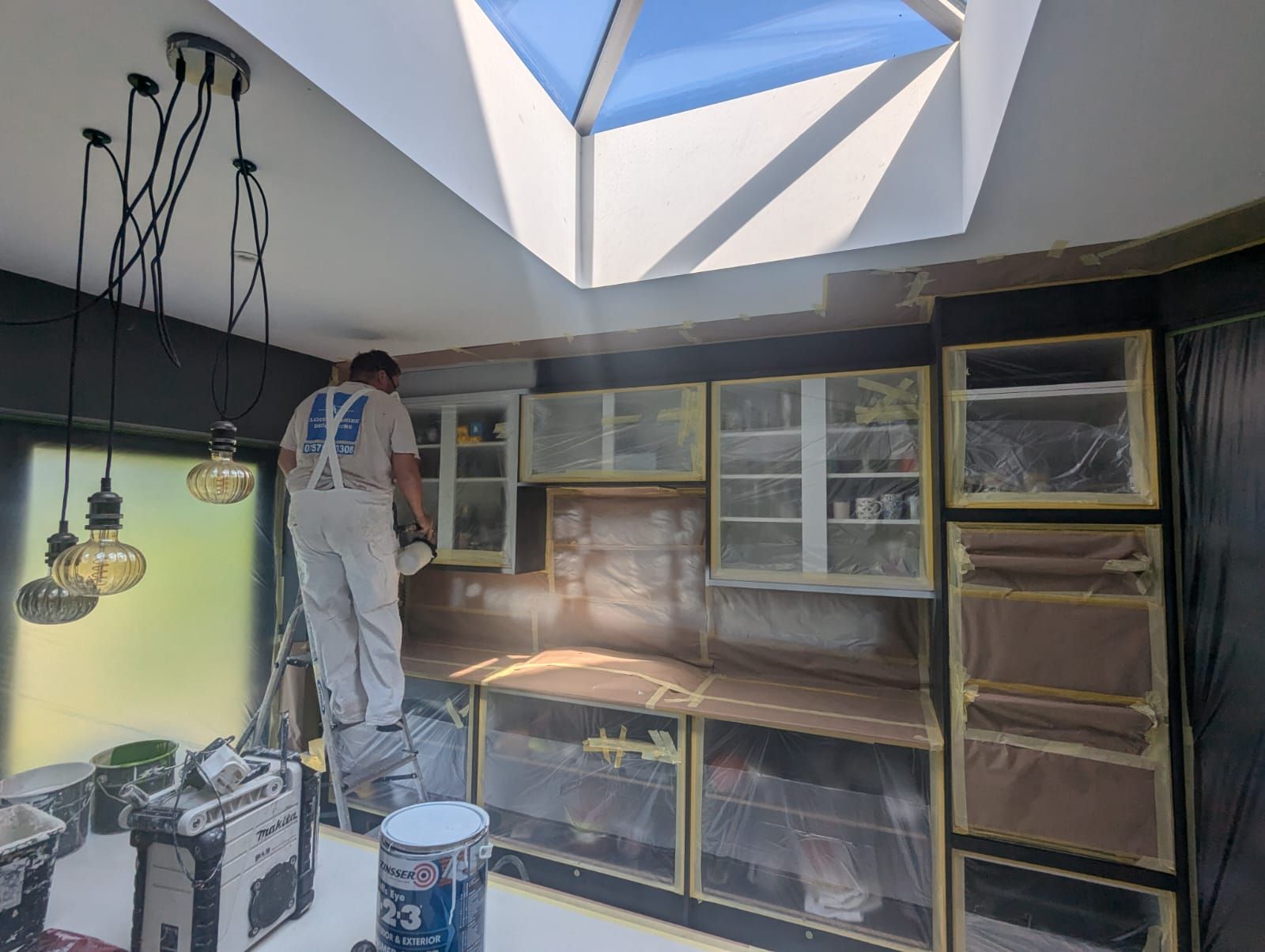 A painter and decorator prepping the kitchen ready for spray painting