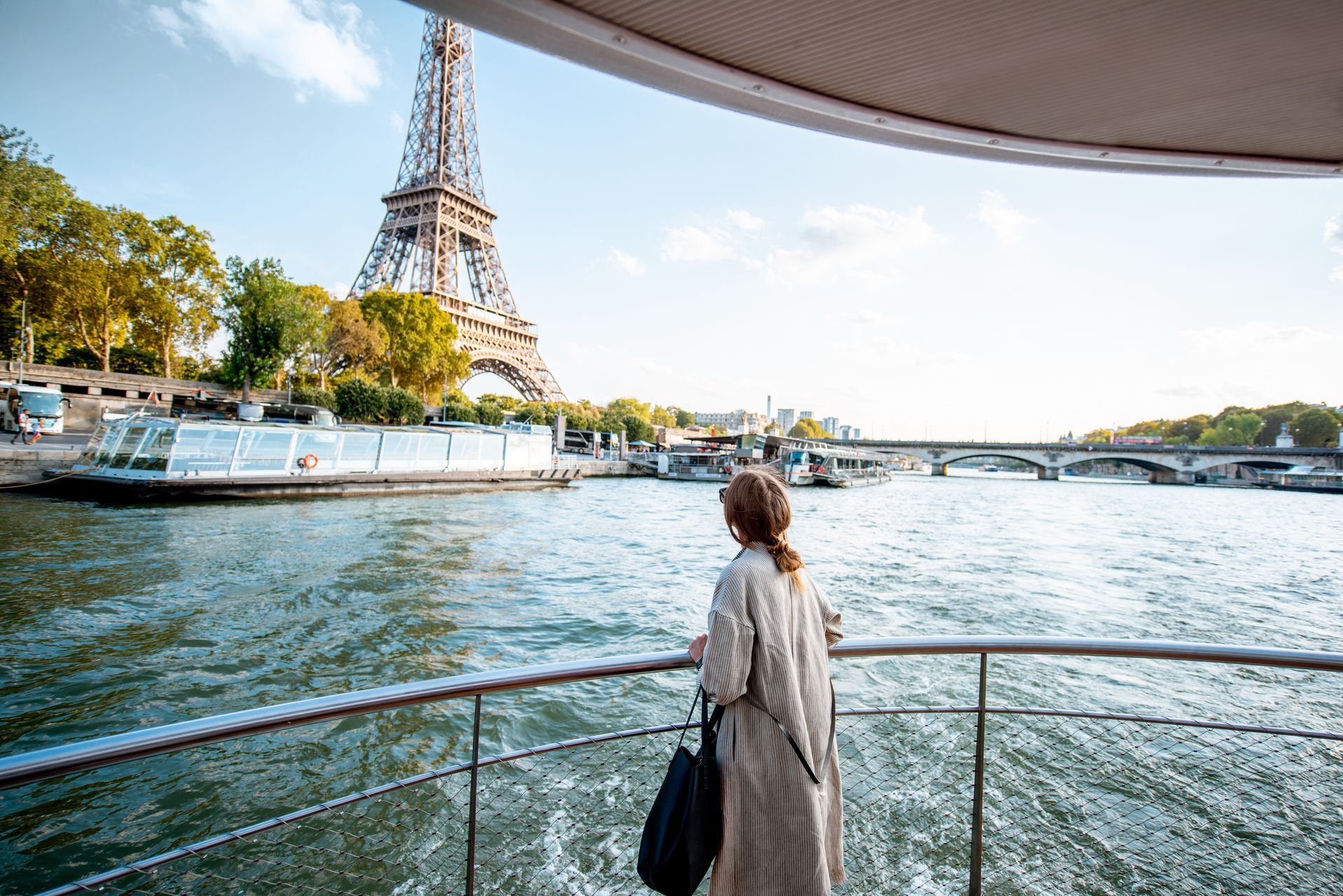 A woman is standing on a boat looking at the eiffel tower.