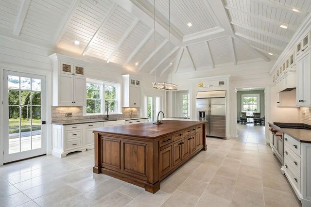 Bright white kitchen with vaulted ceilings, large wood island, and abundant natural light