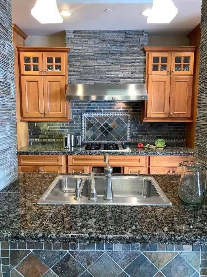 Modern kitchen with granite island, double sink, wood cabinets, and stone backsplash