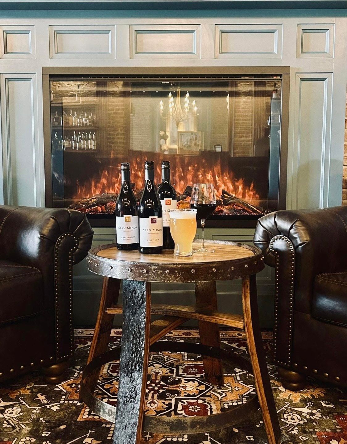 Two glasses of white wine are sitting on a wooden table.