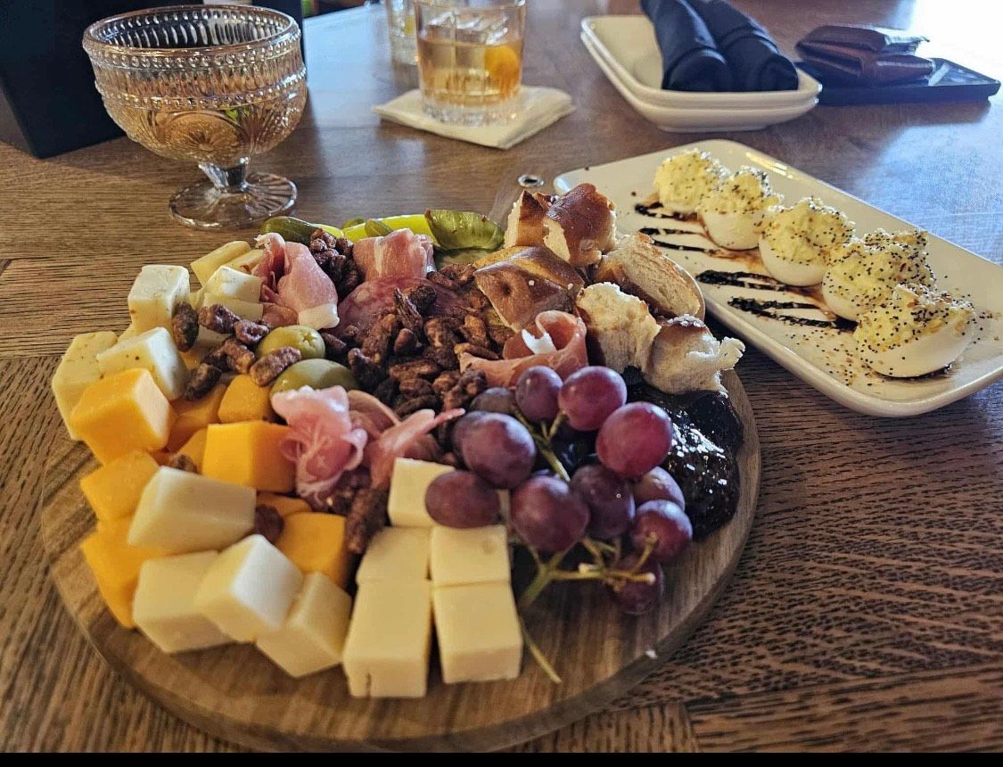 A plate of sliders and a glass of beer on a wooden table.