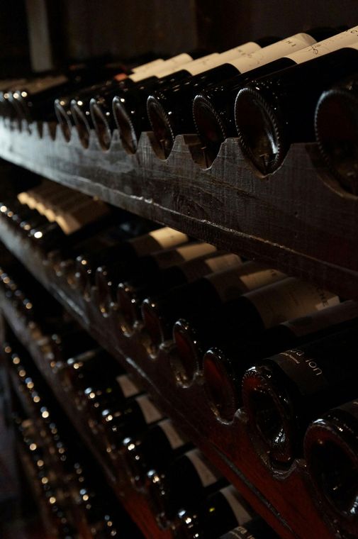 A row of wine bottles are lined up on a shelf