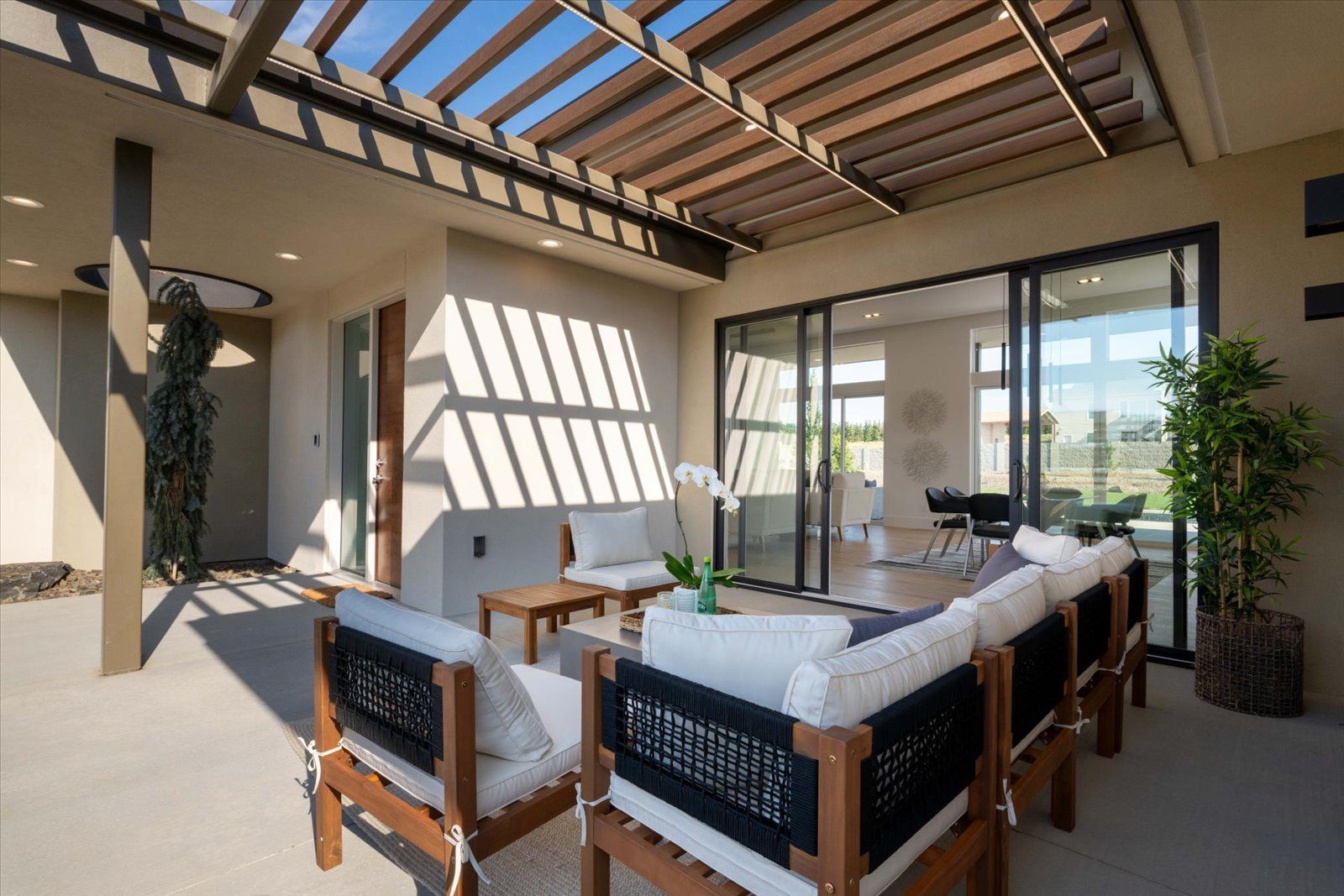 Outdoor patio with seating, open to the interior, shaded by a wooden trellis.