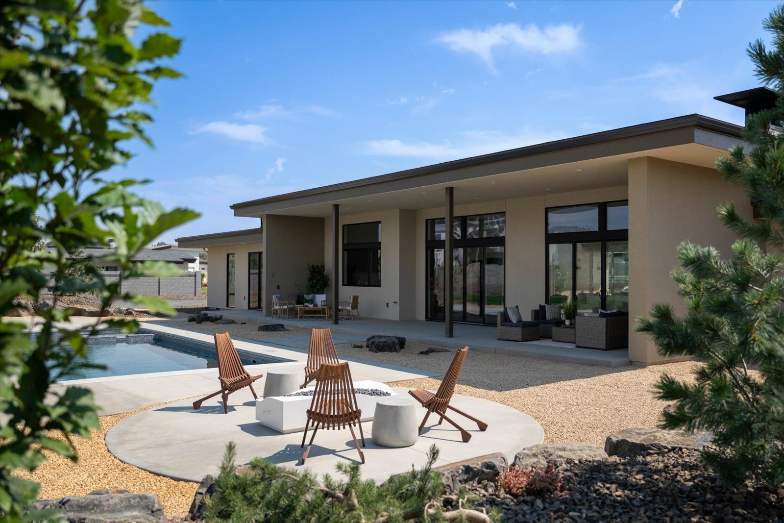Backyard with pool, patio, seating, and a modern house.
