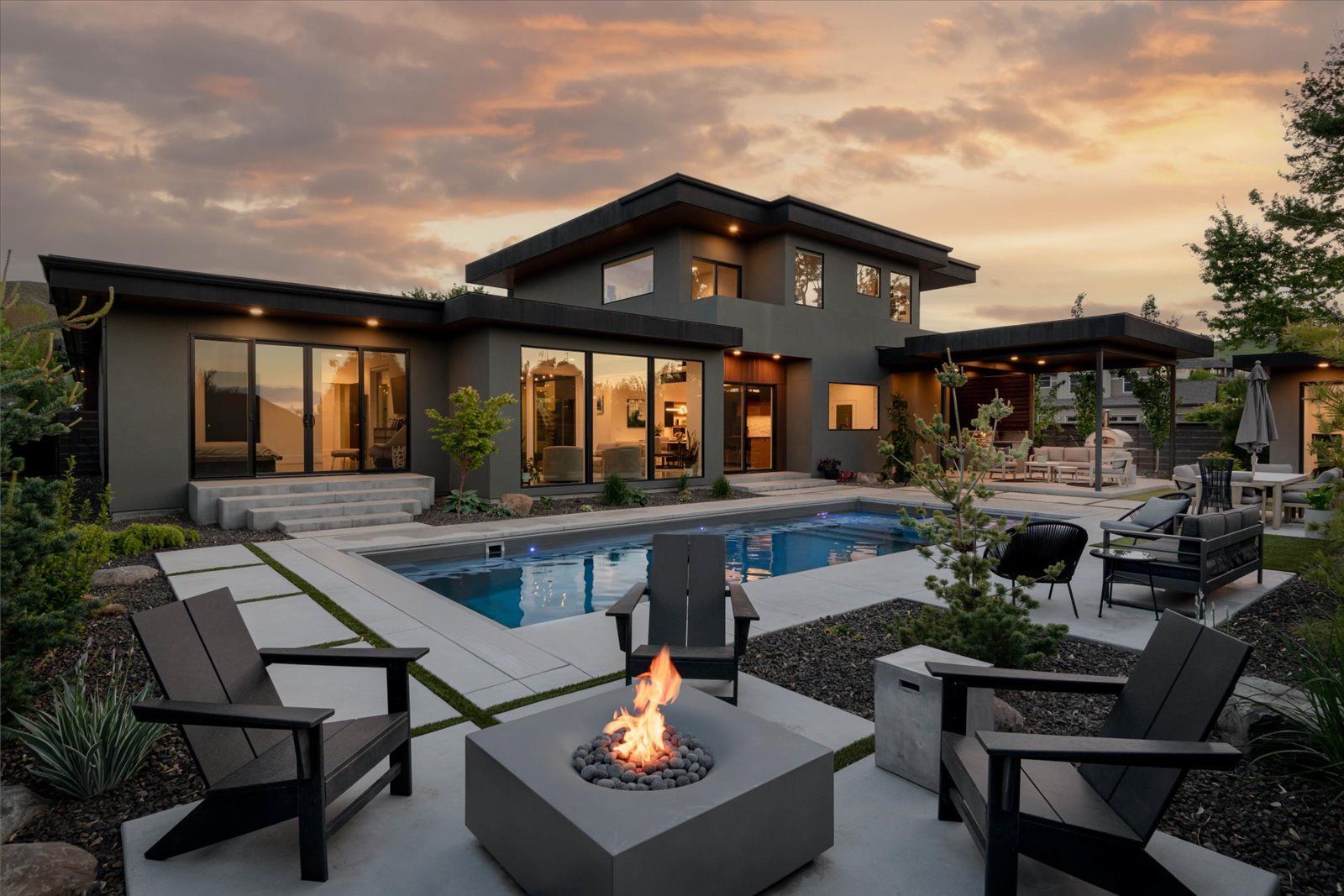 A modern house with a swimming pool and a fire pit in front of it.