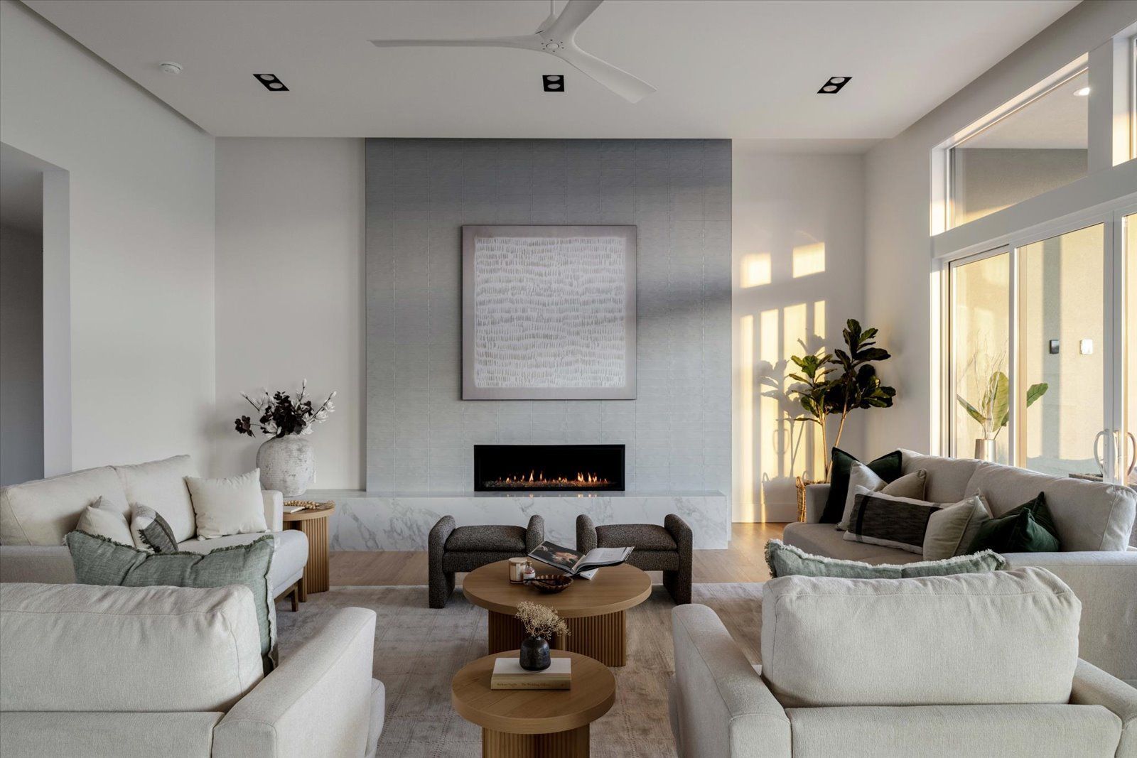 Living room with fireplace, two sofas, wooden coffee tables, and a large window.