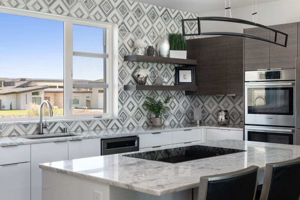 A kitchen with a large island , stainless steel appliances , and a large window.