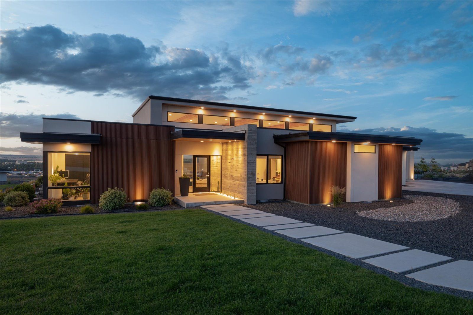 A modern house with a lot of windows is lit up at night.