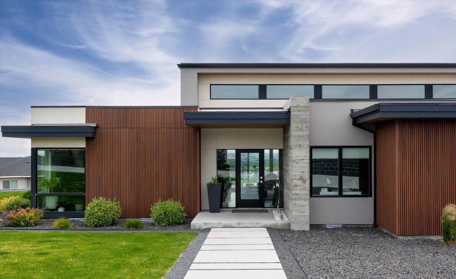 A modern house with a concrete walkway leading to the front door.