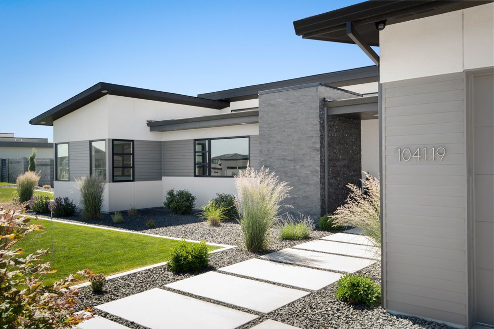 The front of a modern house with a walkway leading to it.