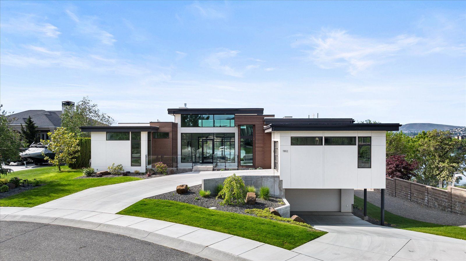 A modern house is sitting on top of a lush green hillside.