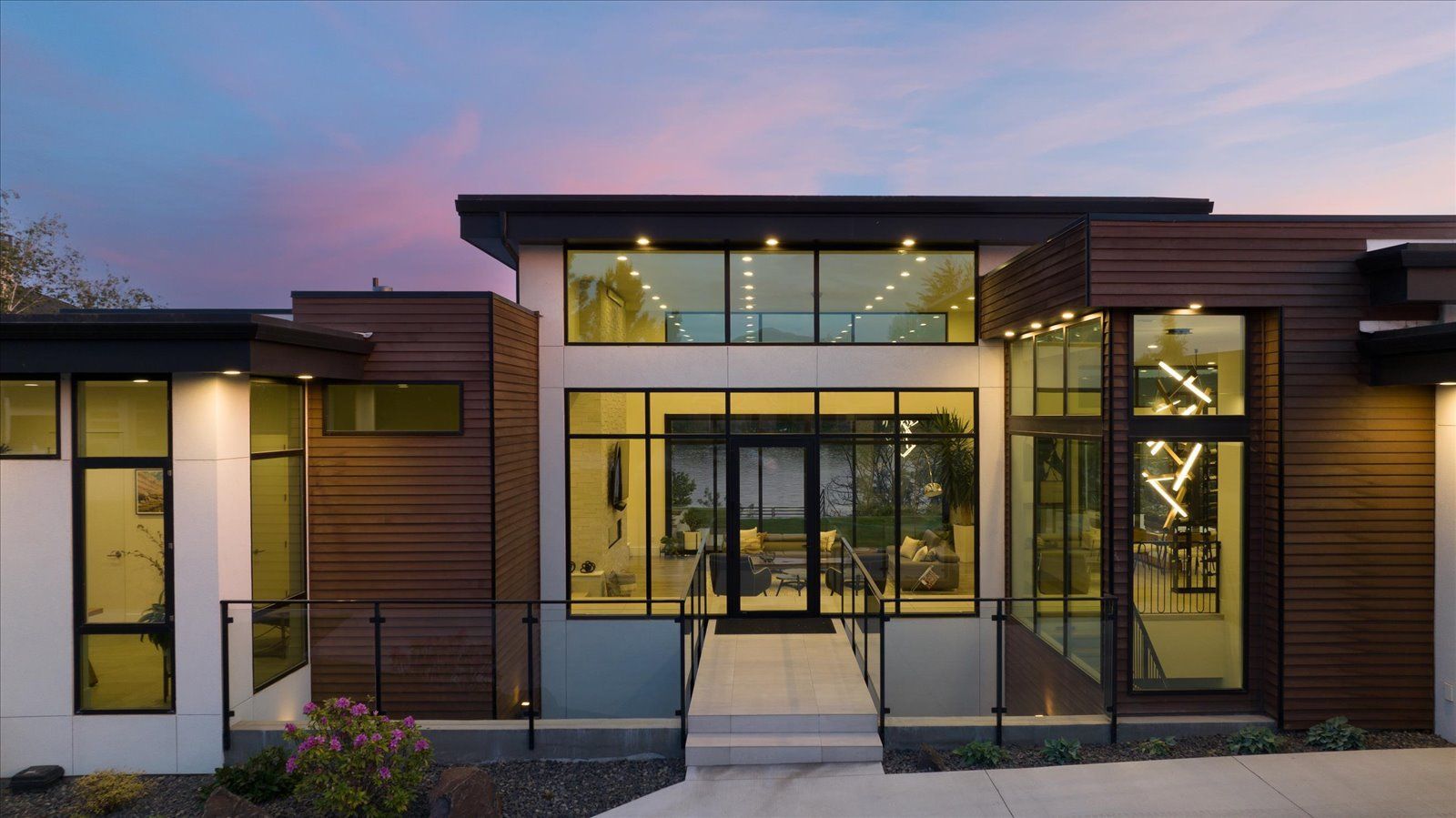 A modern house with a lot of windows and a fence in front of it.