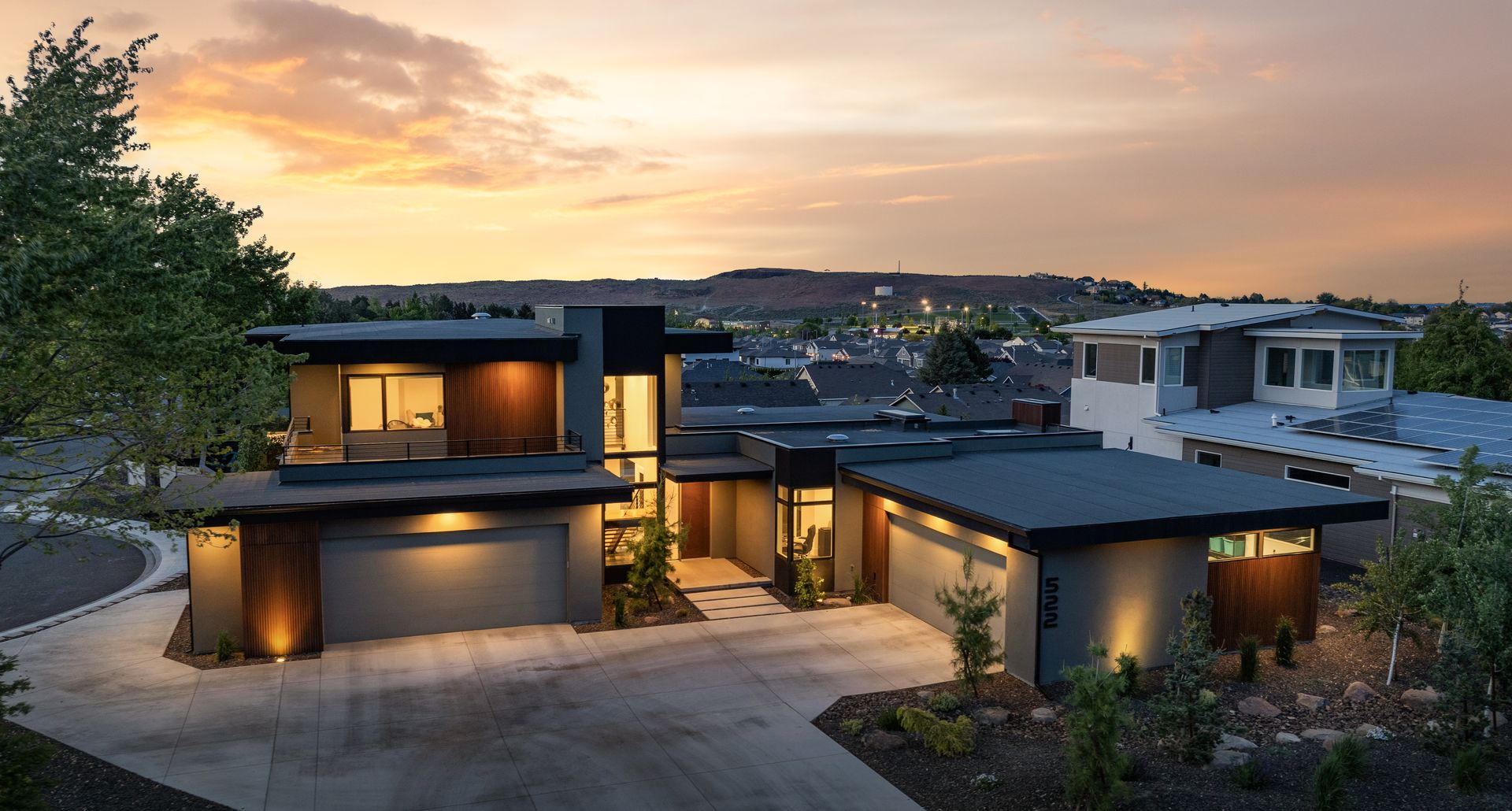Modern home with flat roof, gray exterior, and wooden accents at dusk.