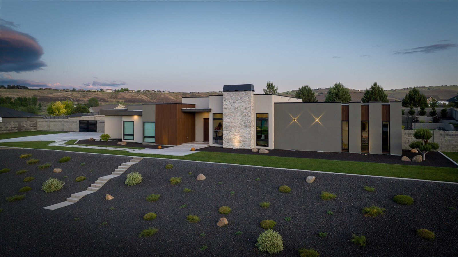 An aerial view of a modern house sitting on top of a lush green hillside.