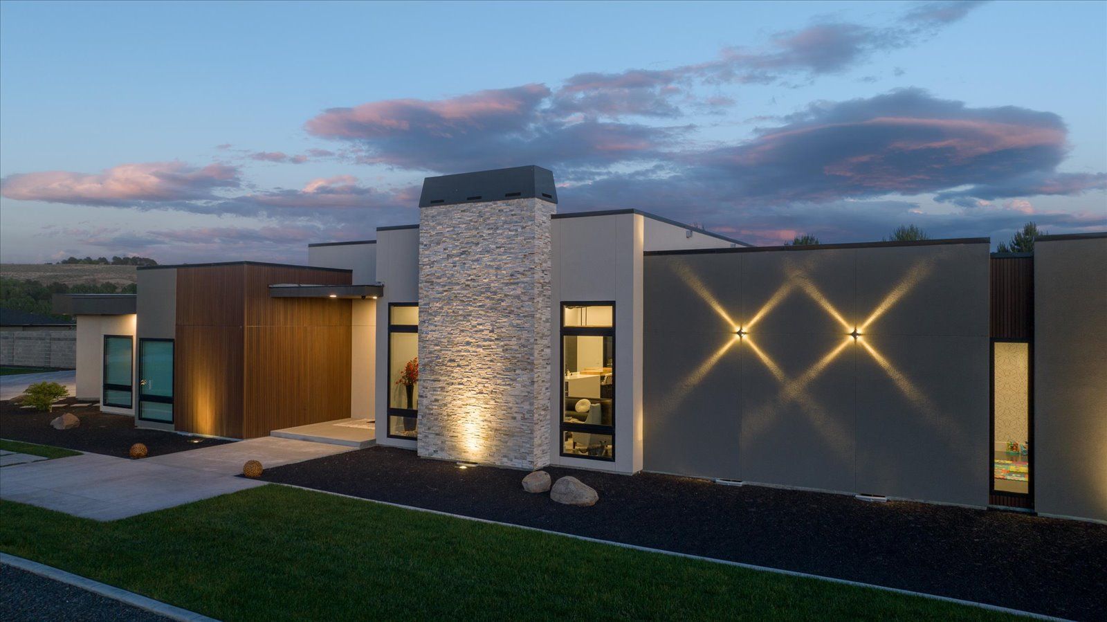 A modern house with a lot of windows is lit up at night.