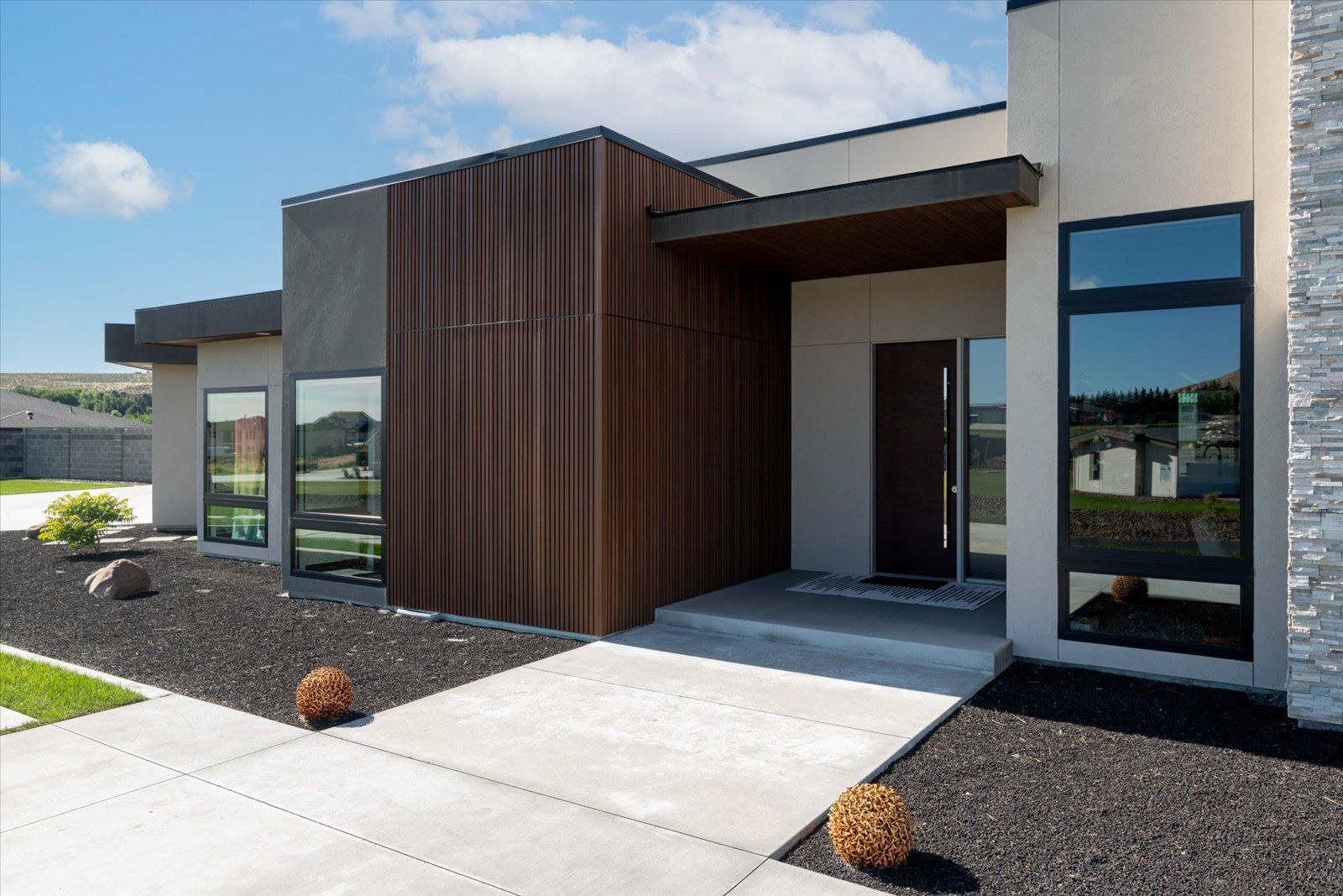 A modern house with a concrete walkway leading to the front door.