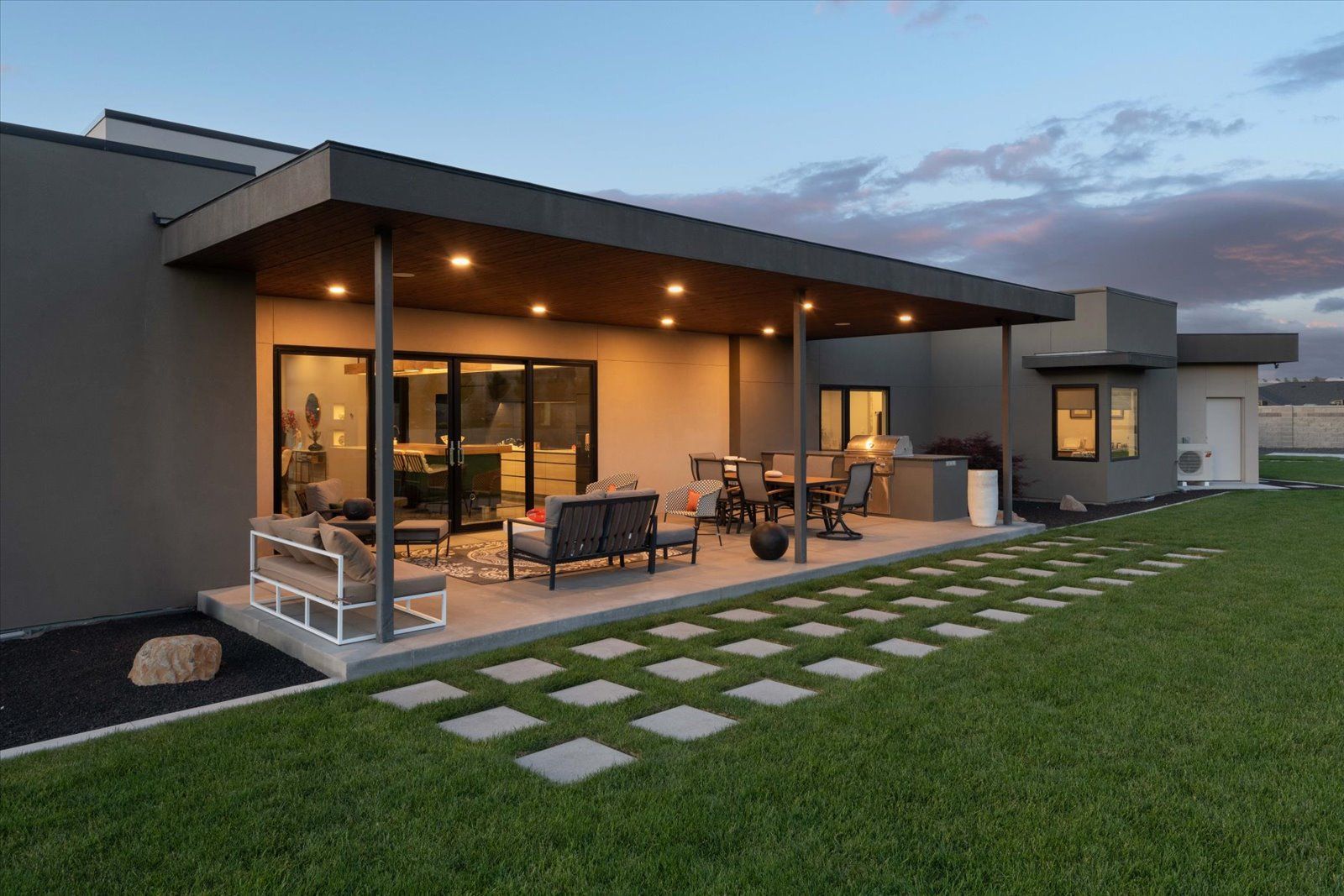 A house with a large covered patio and a lawn in front of it.
