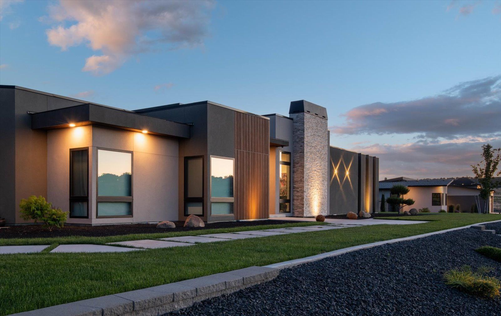 A modern house with a lot of windows is lit up at night.