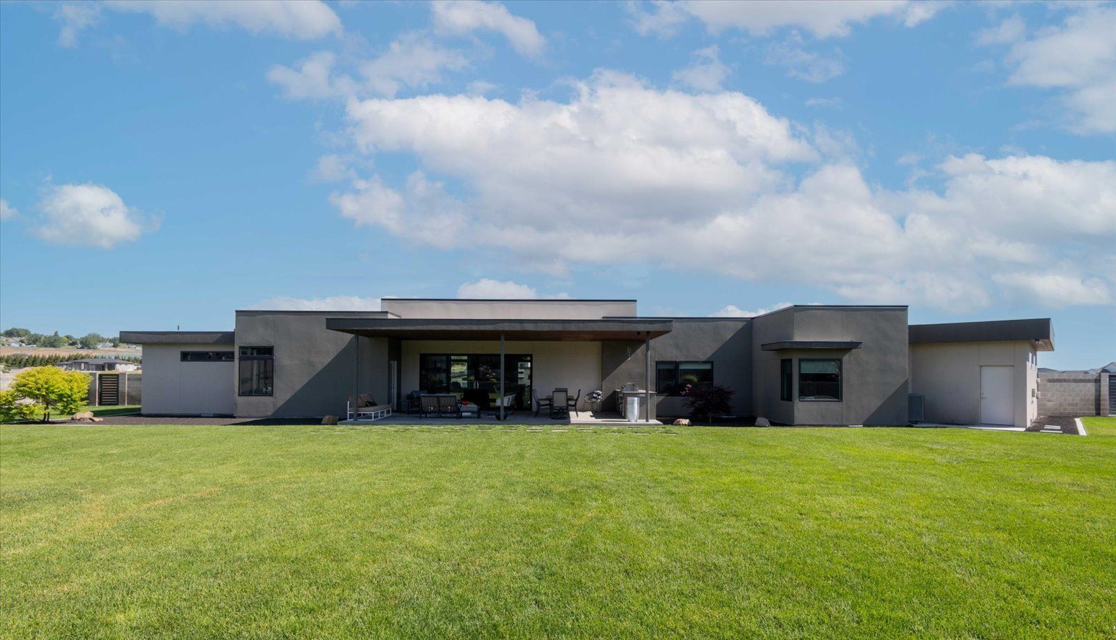 A large house is sitting on top of a lush green field.