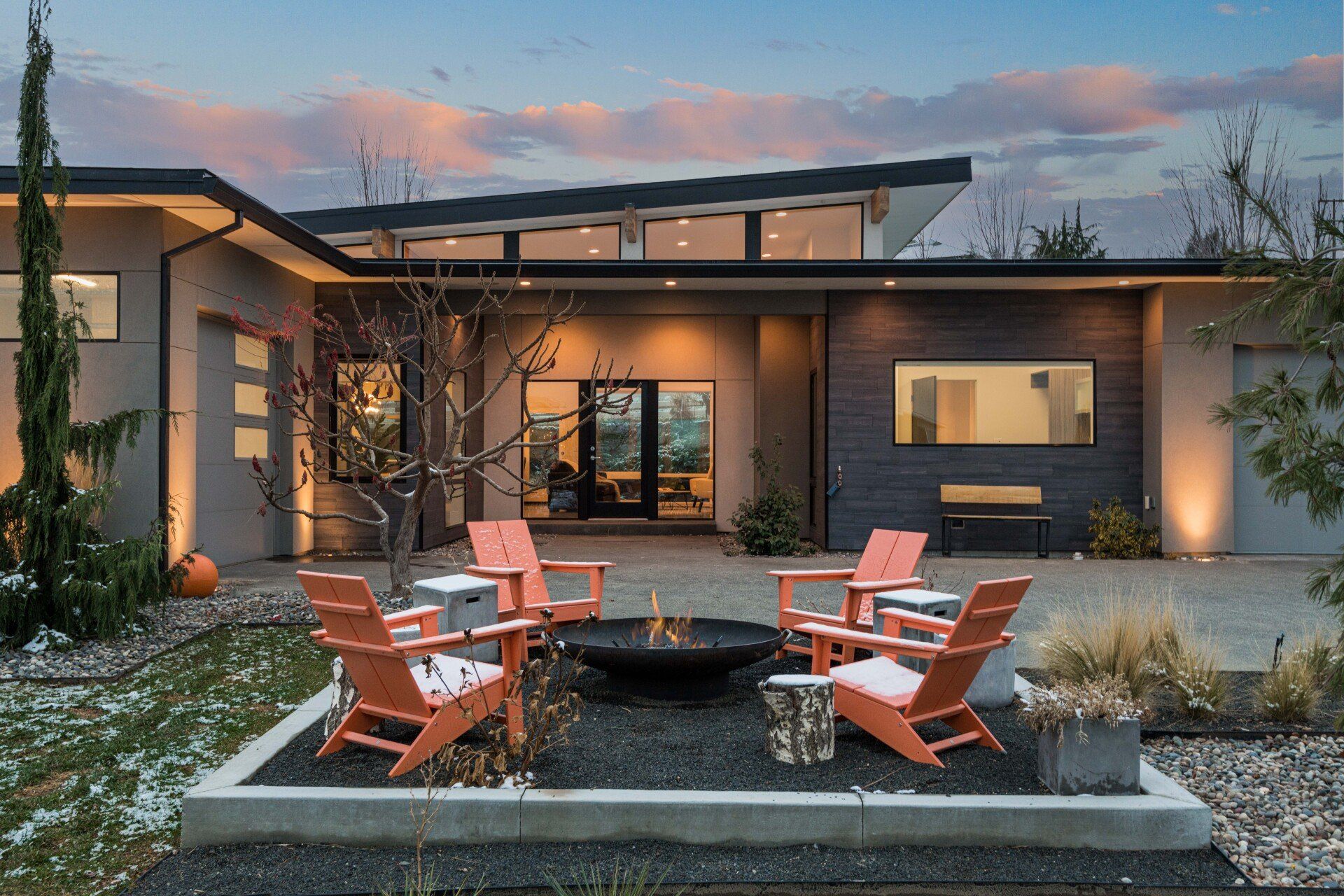 A modern house with a fire pit in front of it.