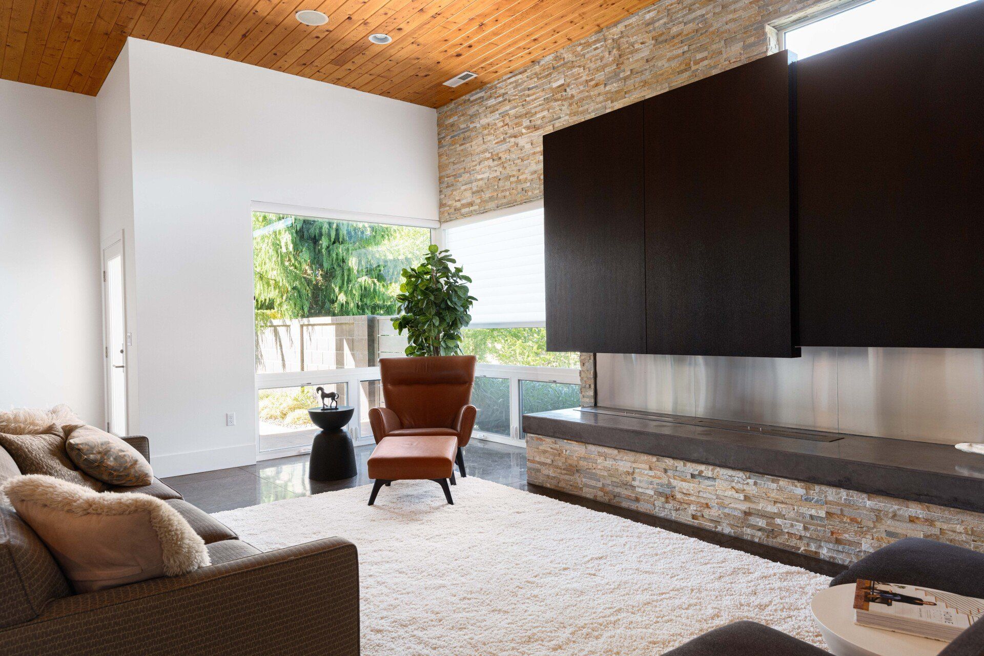 A living room with a couch , chair , ottoman and television.