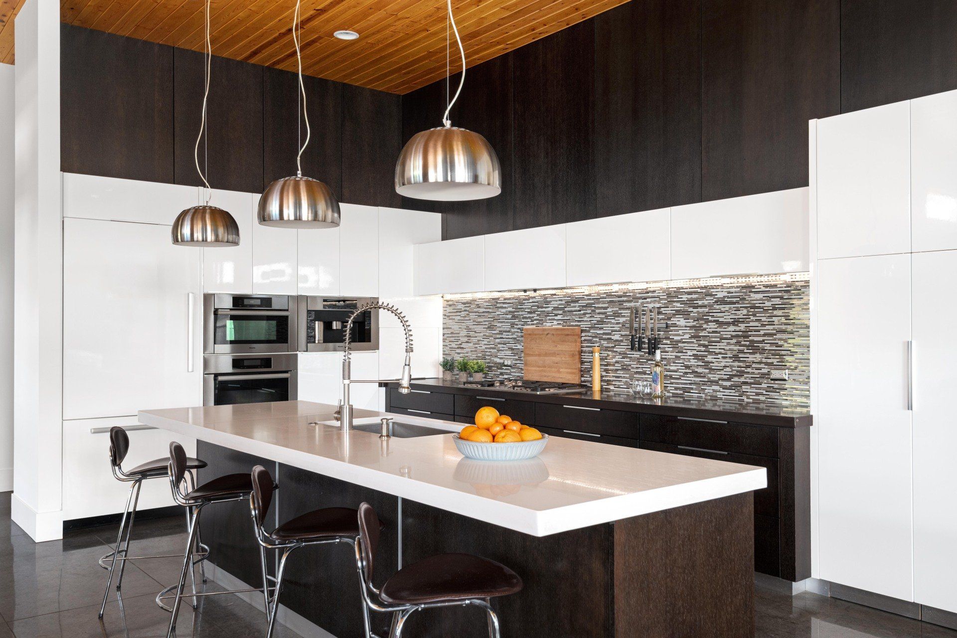 A kitchen with a large island and a bowl of oranges on it