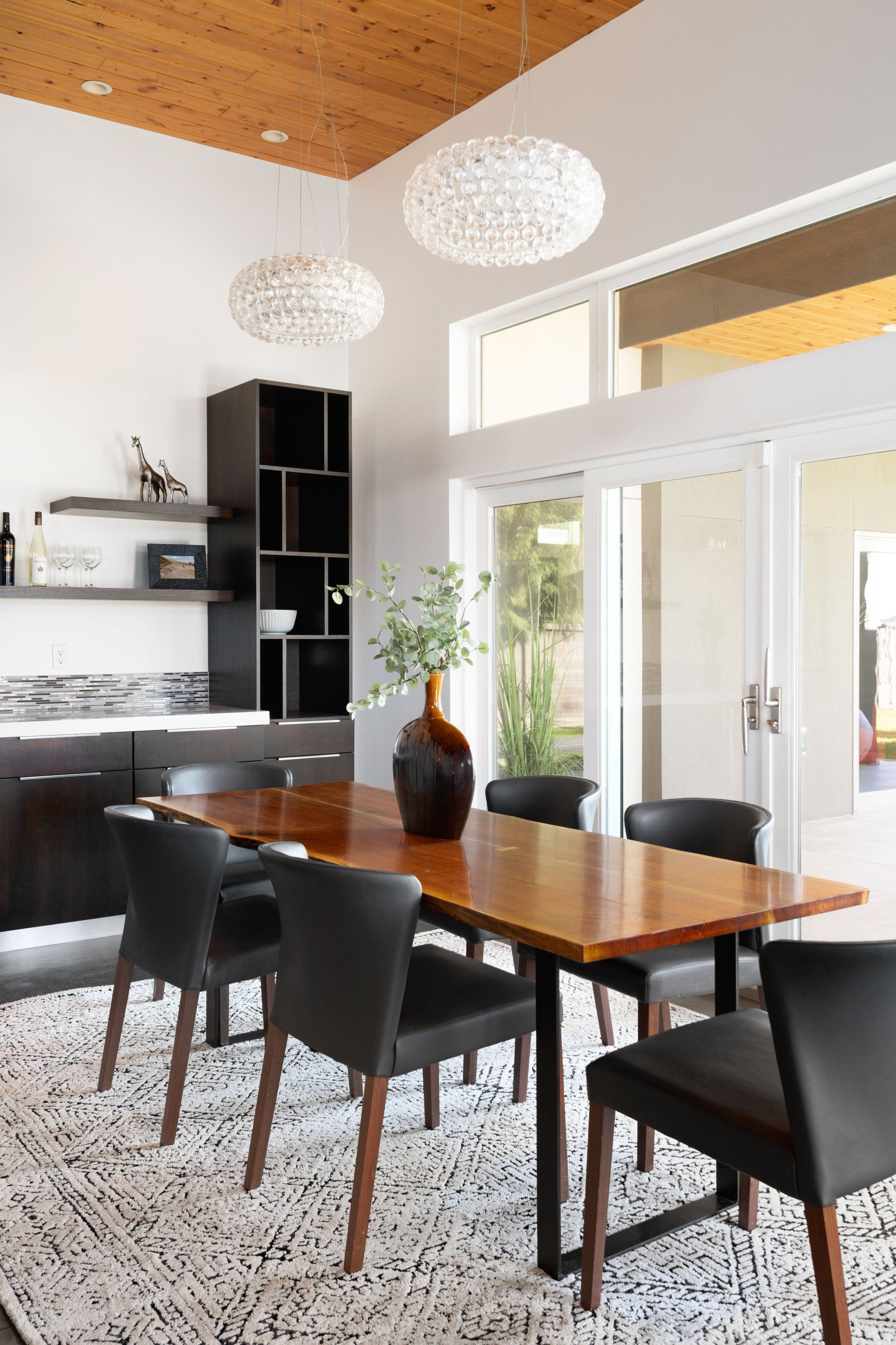 A dining room with a table and chairs and a vase on the table.